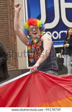 EXETER - MARCH 31:  Festival goers with painted faces hold the rainbow banner at the Exeter Pride 2012 Parade in Exeter City centre  on March 31, 2012 in Exeter, UK