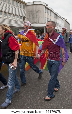 EXETER - MARCH 31: Festival goers hold hands and the rainbow banner at the Exeter Pride 2012 Parade in Exeter City centre on March 31, 2012 in Exeter, UK