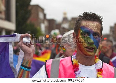 EXETER - MARCH 31: Festival goers with painted faces hold the rainbow banner at the Exeter Pride 2012 Parade in Exeter City centre on March 31, 2012 in Exeter, UK