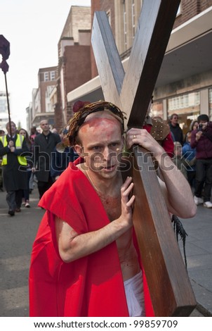 EXETER - APRIL 6: Actor who plays Jesus carries the cross through the streets of Exeter during the Good Friday Walk of Witness in Exeter City Centre on April 6, 2012 in Exeter, UK