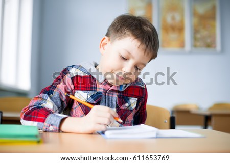 small, boy, schoolboy at the table thinks over the task