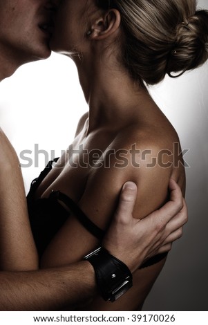 A guy holding a woman\'s shoulder with his hand with passion and kissing her lips