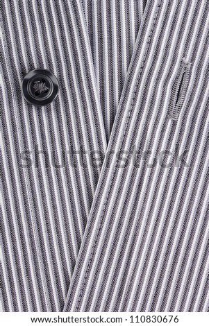 Close-up photograph of a black button on a striped gray pattern.