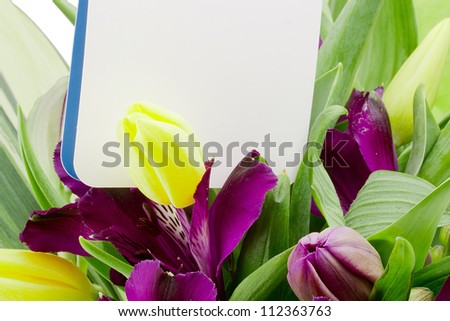 Close-up photograph of purple alstroemeria flowers with a white card for a message.