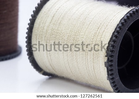 Close-up photograph of a beige spool of thread.