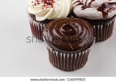 Decorated chocolate cupcake next to other cupcakes.