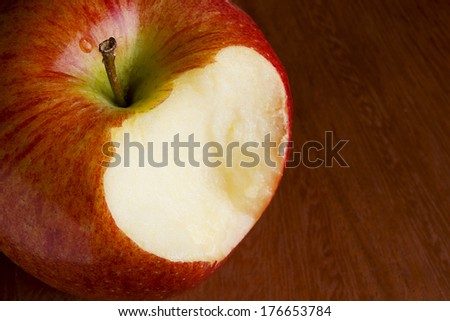 Bitten off apple on a brown wooden surface