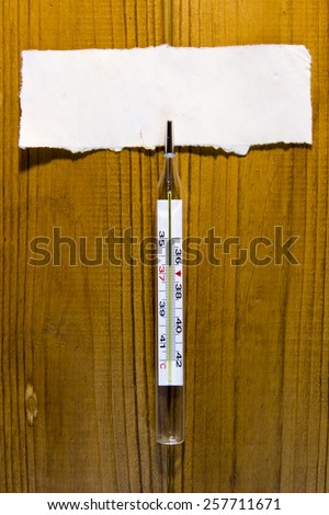 Mercury thermometer to monitor the temperature of the body on a wooden table.