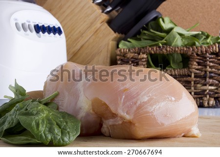 Sliced chicken white meat on a kitchen wooden board.