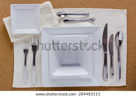 Option table setting with square plates and a complete set of forks, knives and spoons.