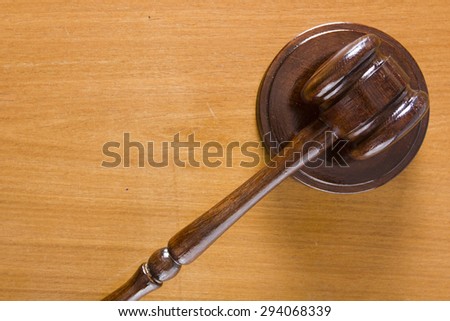 Hammer used in court on a wooden tabletop.