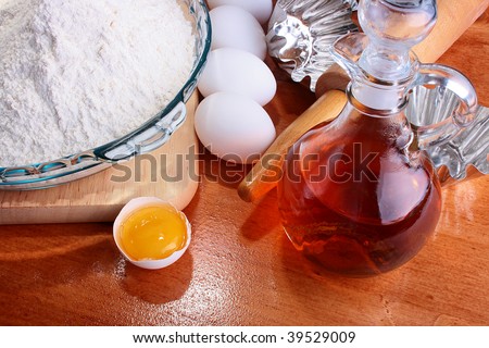The forms prepared for a batch, and also components: a flour, eggs, oil, on a chopping board with Rolling pin.