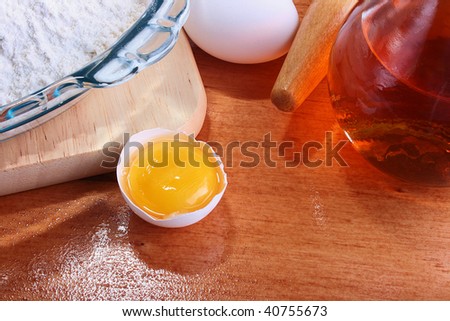The forms prepared for a batch, and also components: a flour, eggs, oil, on a chopping board with Rolling pin.