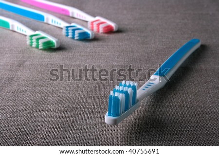 New dark blue tooth-brush on a grey rough fabric.