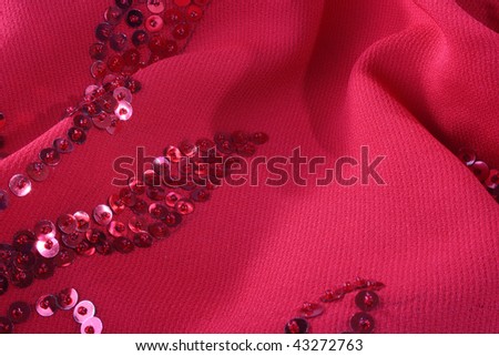 Darkly red fabric with an embroidery from seed bead for use as a background.