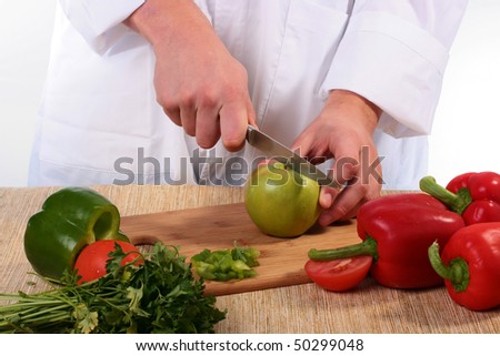 The cook has cut green pepper and starts to cut apple.