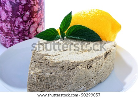 Halvah, yellow lemon and green branch of spice in a plate, on a back background a cup.