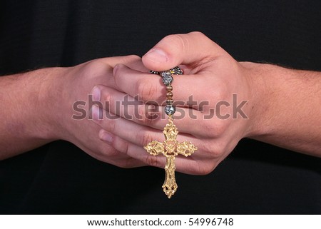 The cross in man\'s hands, the man is dressed in dark clothes.