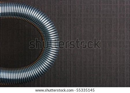 Metal spring deformed on an arch on a brown background.