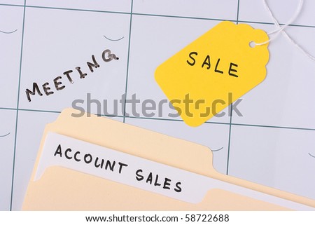 A manila account sales folder laying on a calendar next to a tag.
