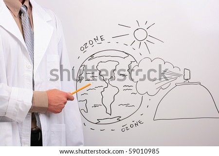 Man in a white lab coat pointing to a drawing of the earth being in danger.