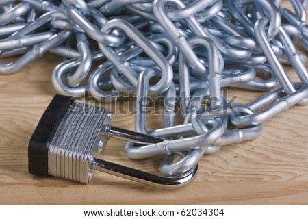Metal lock and chain on a wooden background.