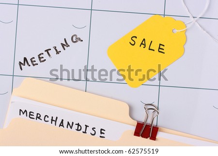 A manila merchandise folder laying on a calendar next to a sale tag.