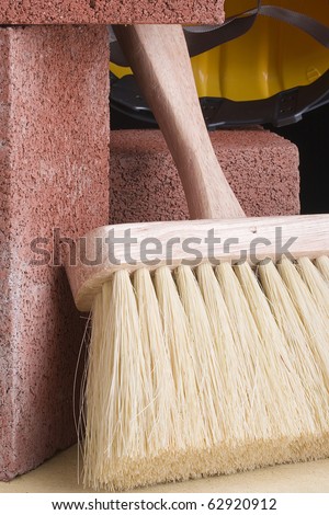 Stonemason\'s brush next to red bricks and a hard hat.