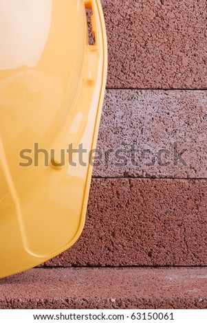 Yellow hard hat on a background of red bricks.