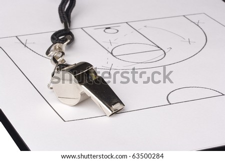 A silver whistle laying on a paper with a basketball game plan on it.