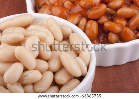 White canned beans in a white ceramic dish with red sauce.