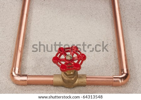 Plumbing copper pipe with a bronze valve on the sand.