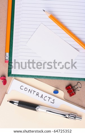 A manila contracts folder laying next to office supplies. Add your text to the business card.