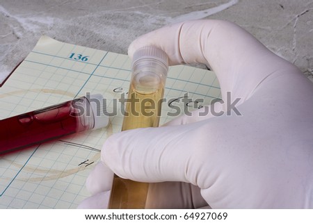 Hand holding a test tube in front of a laboratory notebook.
