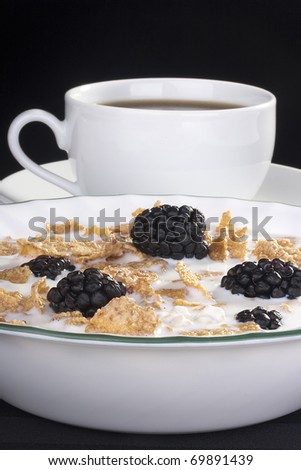 Light morning meal from cereals with berries of a blackberry and milk, in a coffee cup.