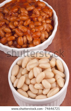 White canned beans in a white ceramic dish with red sauce.