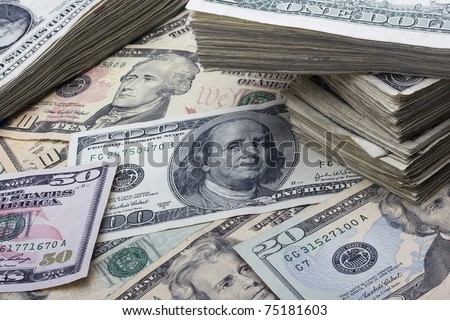 Variety of American money laid out under a stack of cash.