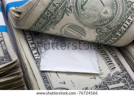 Small sealed bag with drugs laying in a stack of cash.