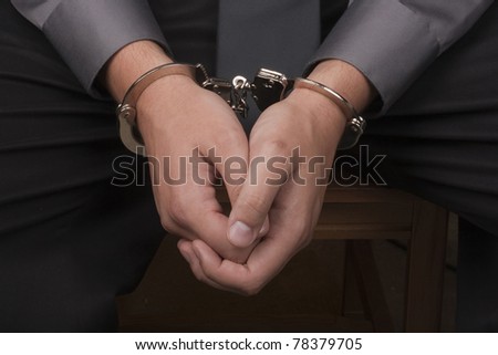 Close-up of hands handcuffed, arrested for questioning.