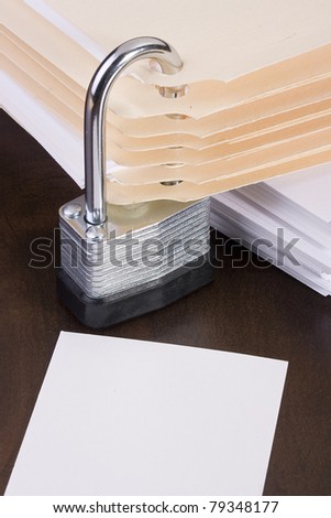 Stack of manila folders closed with a metal lock. Add your text to the white space.