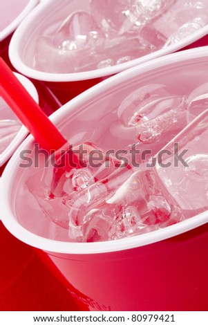 Water and ice in a red disposable cup.