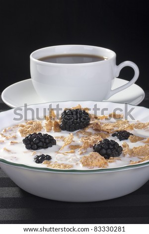 Light morning meal from cereals with berries of a blackberry and milk, in a coffee cup.