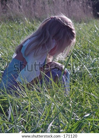 Young girl, playing dress up,  watching something in the grass  while playing outside