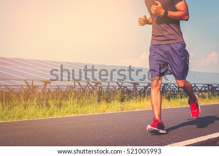 handsome man running on road with solar power plant in morning ;Healthy lifestyle with green energy