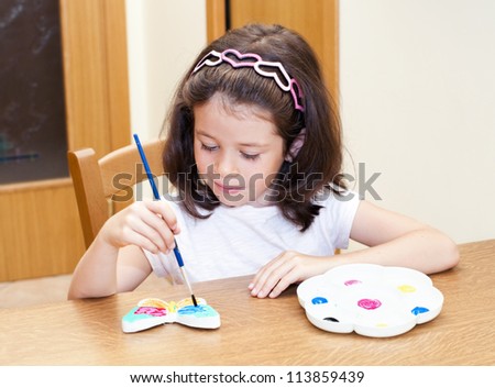 Child painting a butterfly with a color palette