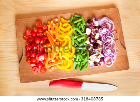 Cut vegetables of rainbow colors on wooden cutting board