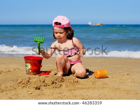 Child playing on the beach and building sand castle