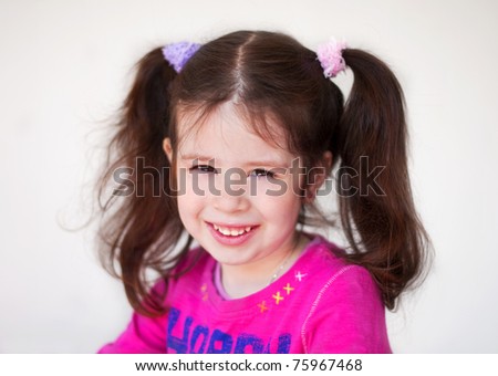 Portrait of a smiling cute little girl with long hair tails