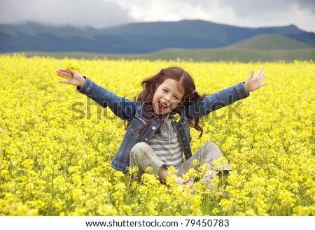 Happy girl in a field of yellow flowers with her hands up