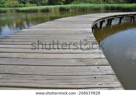 Right curve wooden bridge path in lake at wetland park